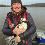 Photo of Tricia Miller in a boat holding an osprey